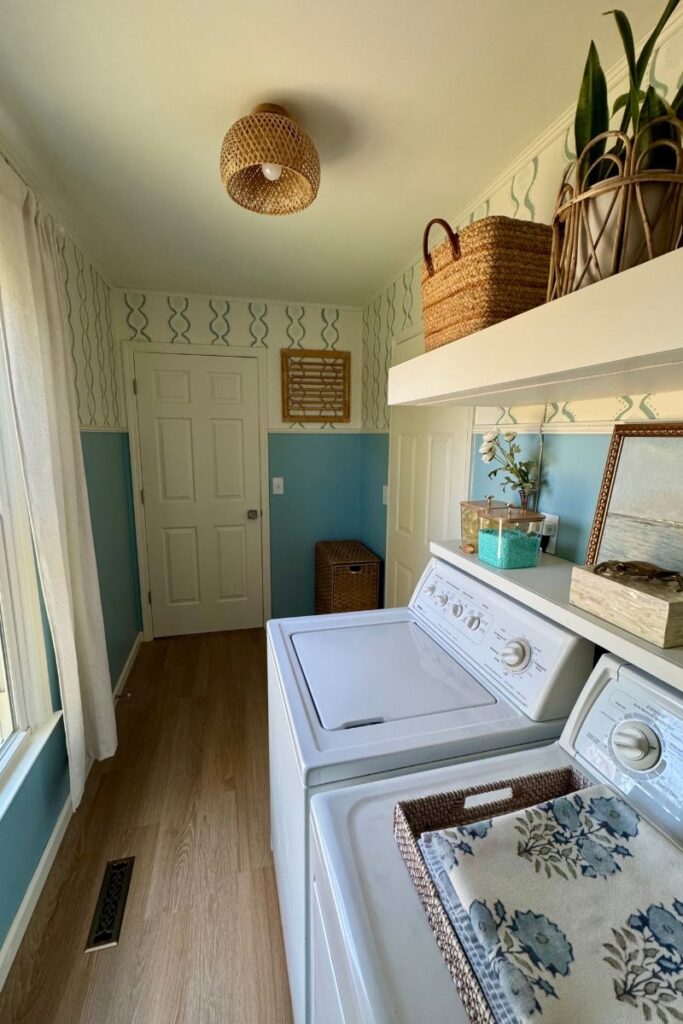 Coastal blue and white laundry room with woven baskets and coastal artwork by Lakeshore Interior Design